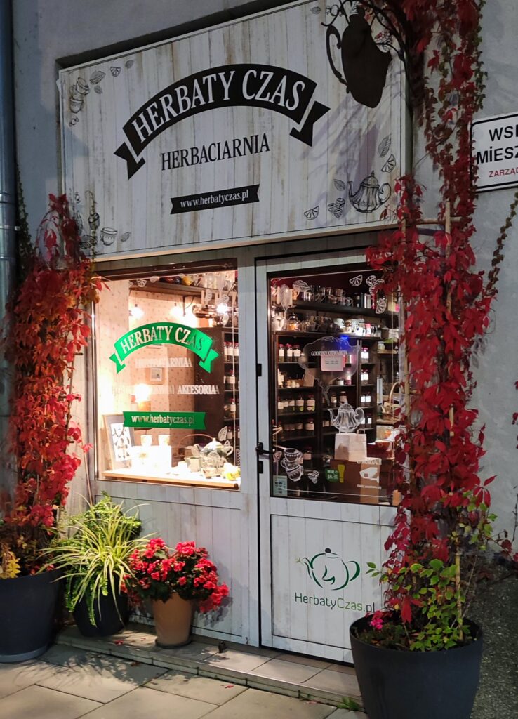 Herbaciarnia w Warszawie Herbaty Czas Powiśle Zdjęcie przedstawia front sklepu wieczorem z zapalonym delikatnym światłem i napisem herbaciarnia nad wejściem